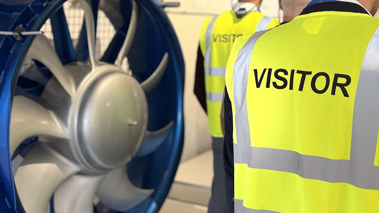 Fachtagung Technische Sauberkeit 2026 - werksführung bei Voith. Teilnehmer werden von hinten Richtung Sprecher fotografiert und tragen Visitor Westen in gelb