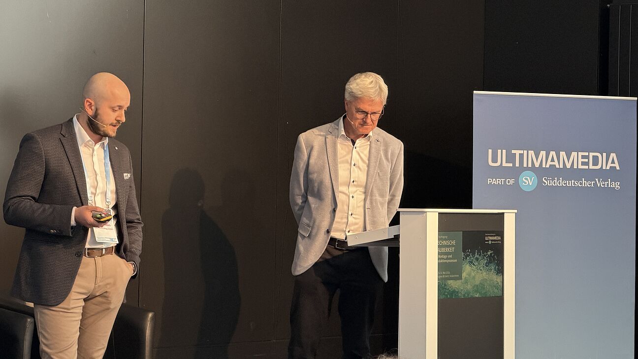Fachtagung Technische Sauberkeit 2026 - Speaker auf der Bühne hält seinen Vortrag mit einer Präsentation die er den Teilnehmern zeigt