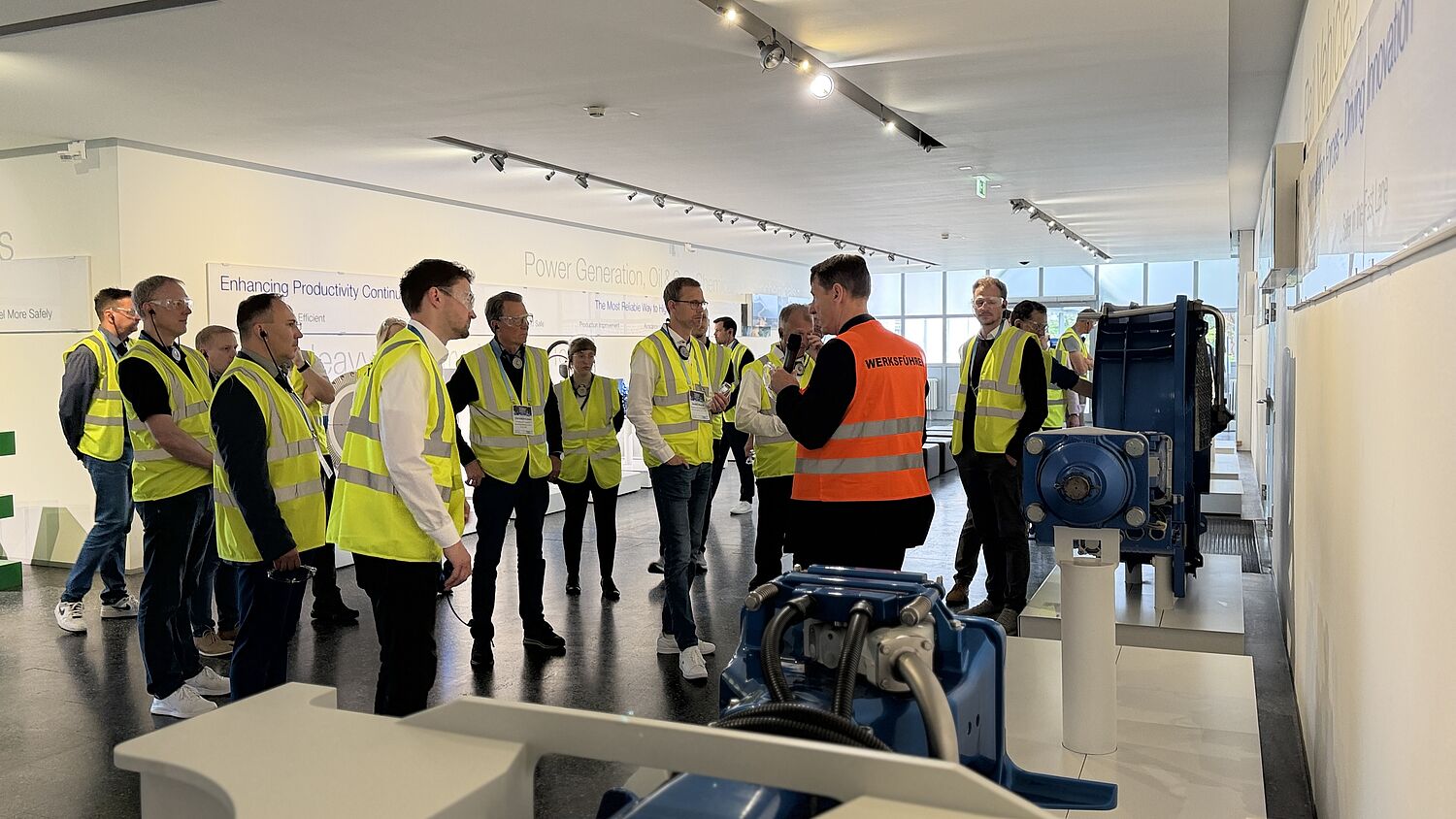 Werksführung bei Voith - Teilnehmer tragen Visitor Weste und schauen Richtung Sprecher.