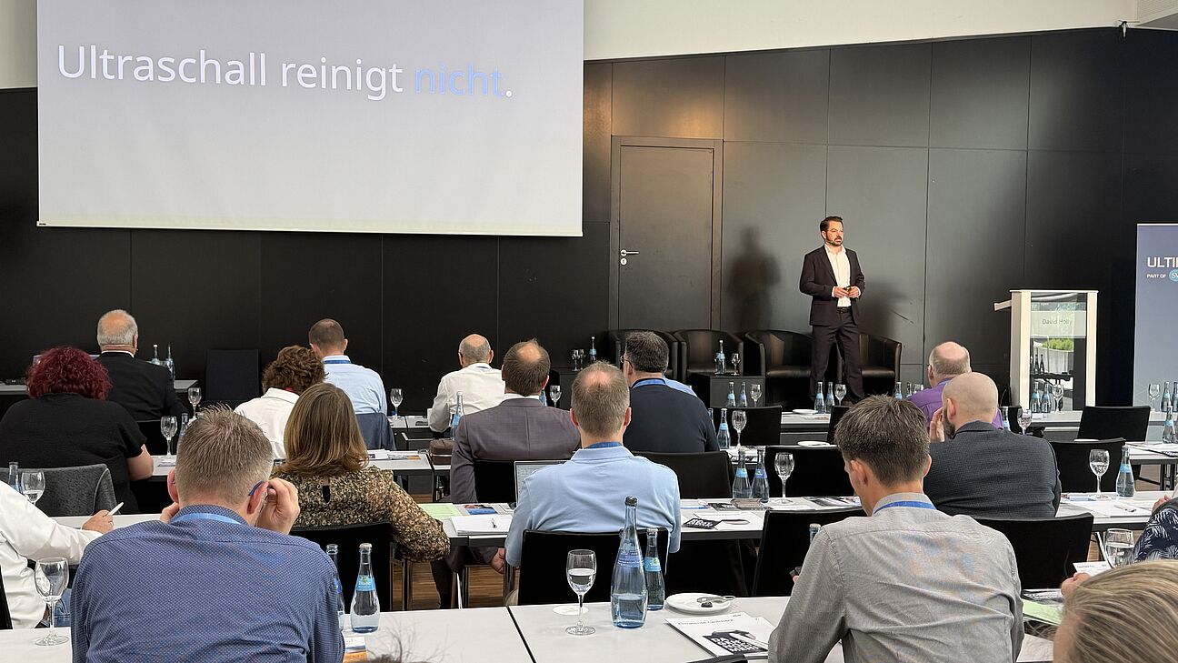 Fachtagung Technische Sauberkeit 2026 - Speaker auf der Bühne hält seinen Vortrag mit einer Präsentation die er den Teilnehmern zeigt