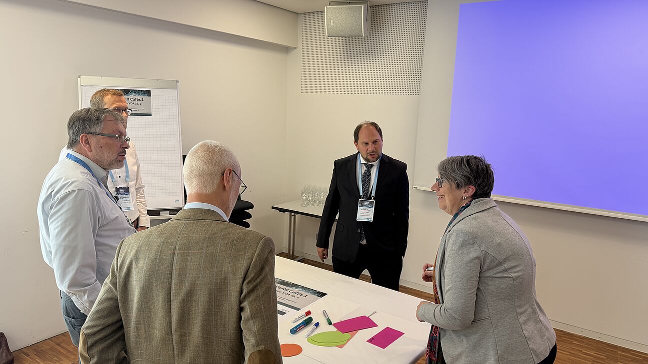 Fachtagung Technische Sauberkeit 2026 - Workshop 4 Teilnehmer stehen um einen Tisch und diskutieren über Technische Sauberkeit